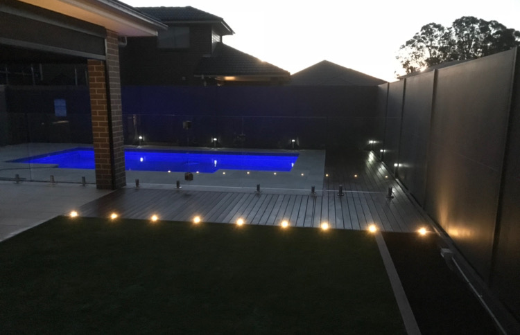Backyard pool at dusk with composite decking and ambient lighting.