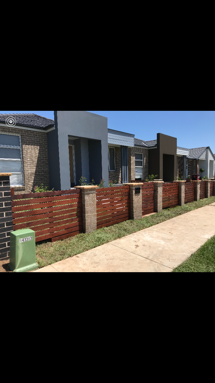 Horizontal timber slat feature fence with rendered piers fronting a row of houses.